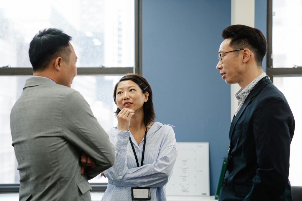 Three business colleagues engage in a thoughtful discussion in a modern office setting.
