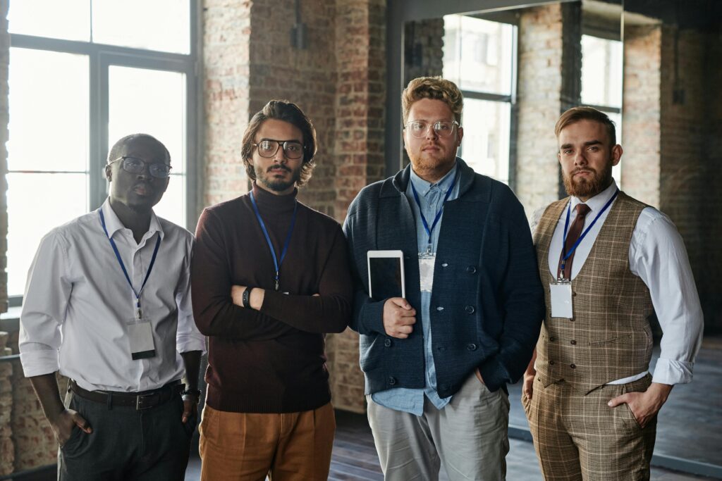 Portrait of a diverse group of four serious professionals standing indoors with tablets.